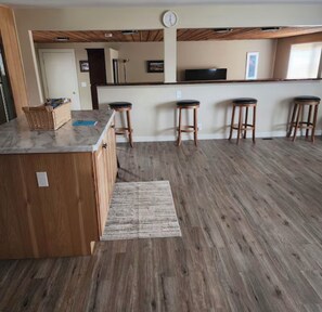 Una cocina con una isla de madera, taburetes de bar y una alfombra en el suelo.