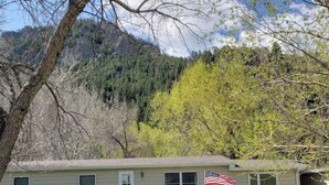A single-story house with a front porch, a small deck, and an American flag on the side. - River Cabin is in Cascade right on the Missouri River (Cascade)