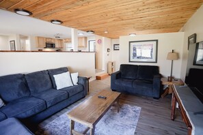 Una sala de estar con dos sofás, una mesa de centro y un mueble para televisión.