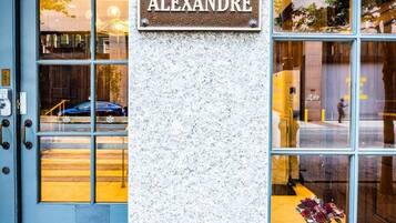 A building entrance with a sign reading 'THE ALEXANDRE' and a blue door.
