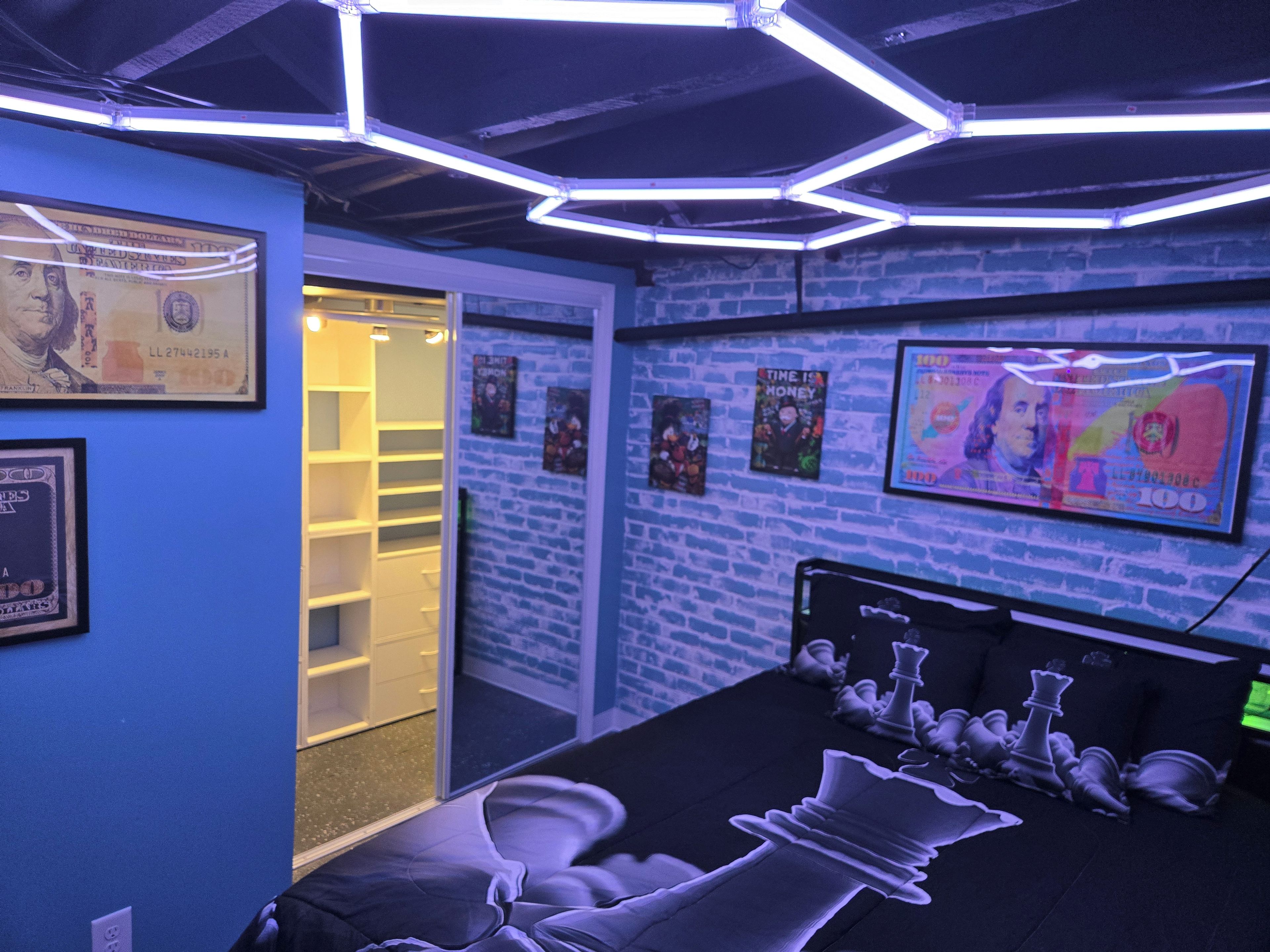 A room with a bed, a closet, and a wall with framed pictures.