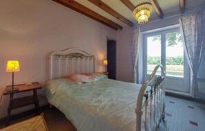 A bedroom with a bed, bedside lamps, a window with curtains, and a chandelier. - Charmant studio au calme (Les Gours)