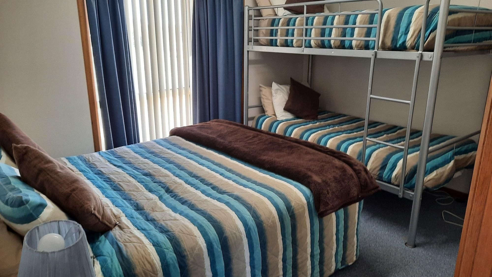 A bunk bed room with striped bedding and a brown throw blanket.