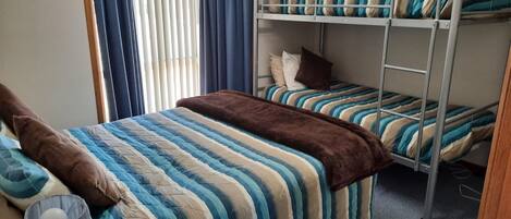 A bunk bed room with striped bedding and a brown throw blanket.
