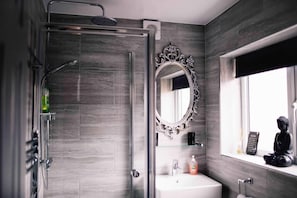 A modern bathroom with a shower, a sink, a mirror, and a window.