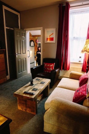 A living room with a sofa, a coffee table, and a door leading to another room. - Coalminer's Cottage (Gateshead)