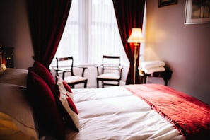 A hotel room with a bed, a chair, a table, and a lamp. - Coalminer's Cottage (Gateshead)