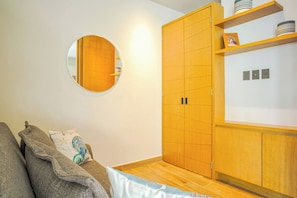 Un dormitorio con cama, armario, espejo y estante con adornos.
