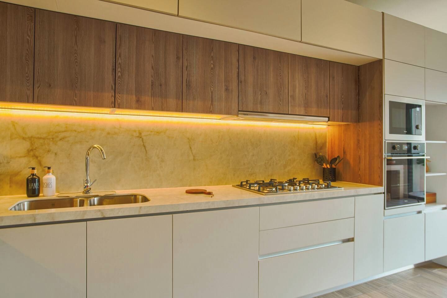 A modern kitchen with a built-in stove, a sink, and wooden cabinets.