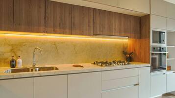 A modern kitchen with a built-in stove, a sink, and wooden cabinets.