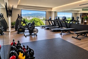 Ein Fitnessstudio mit Cardiogeräten, Gewichten und Blick auf die Stadt.