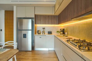 Una cocina compacta con estufa a gas incorporada, un refrigerador y una cafetera.