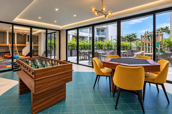 Una habitación con mesa de futbolín, mesa de billar y sillas amarillas.