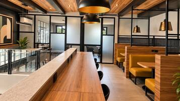 A modern interior with a long wooden table, yellow chairs, and black pendant lighting.