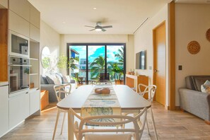 A modern kitchen with built-in appliances, a dining area with a large table and chairs, and a view of the outdoors. - Stylish 2BR • Infinity Pool & Coworking  & GYM• Versalles (Puerto Vallarta)