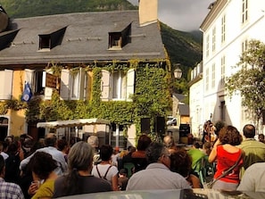 A crowded outdoor market with buildings and a mountain in the background. - Hv¥tel Les Templiers (Luz-Saint-Sauveur)