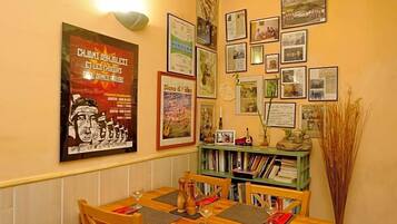 Un coin repas avec une table en bois dressée pour deux personnes, entourée d’étagères remplies de livres.