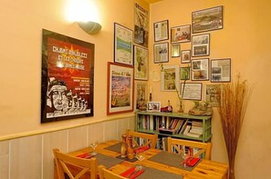 Un comedor con una mesa de madera dispuesta para dos personas, rodeado de estanterías llenas de libros.