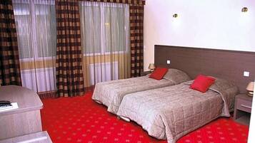 Een hotelkamer met twee bedden, een bureau en een rood tapijt.