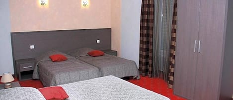 Hotellihuone, jossa on kaksi sänkyä, vaatekaappi ja punainen matto.