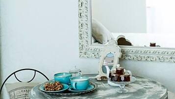 Zona pranzo con tavolo rotondo, sedie e specchio con cornice decorata.