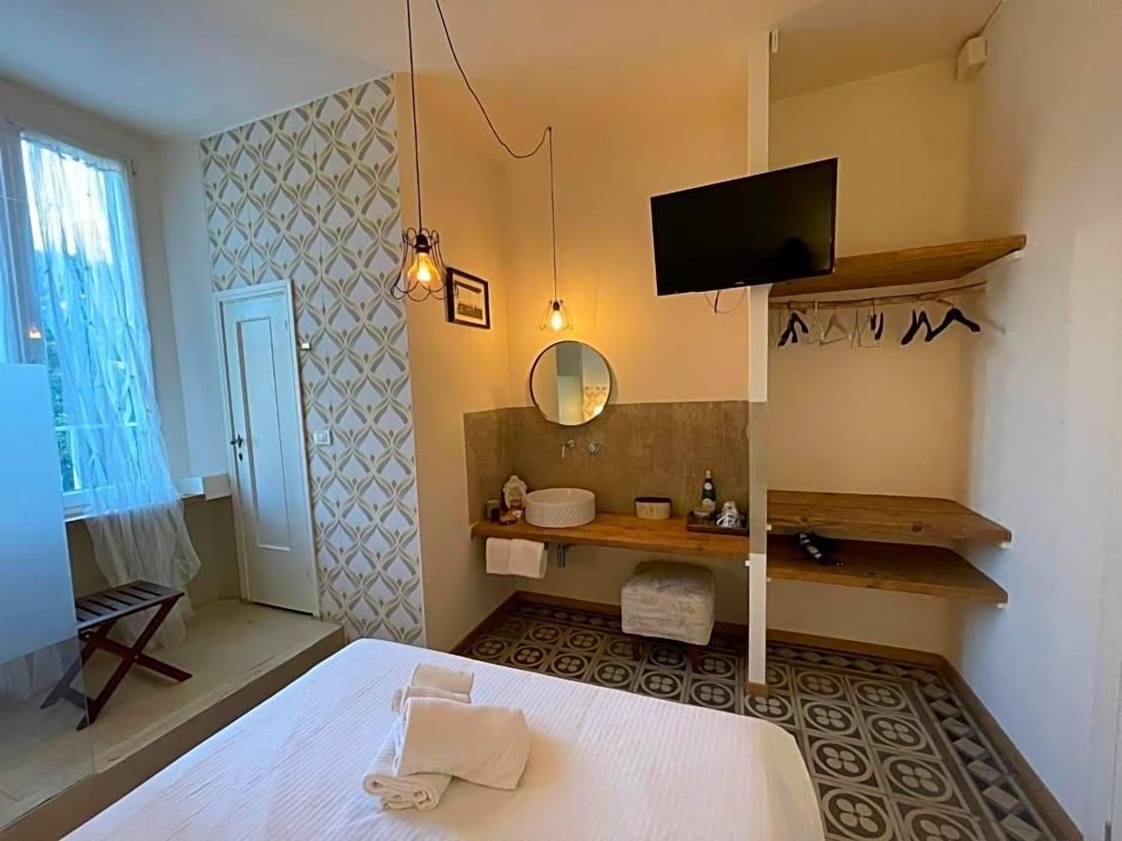 A hotel room with a bed, a television, a mirror, a sink, and a patterned floor.