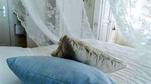 A bed with a blue pillow and a decorative pillow with frayed edges. - Locanda Garzelli (Livorno)