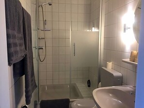 A bathroom with a glass-enclosed shower, a bathtub, a sink, and a toilet. - Hotel Wuelfers Gasthaus (Groß Ippener)