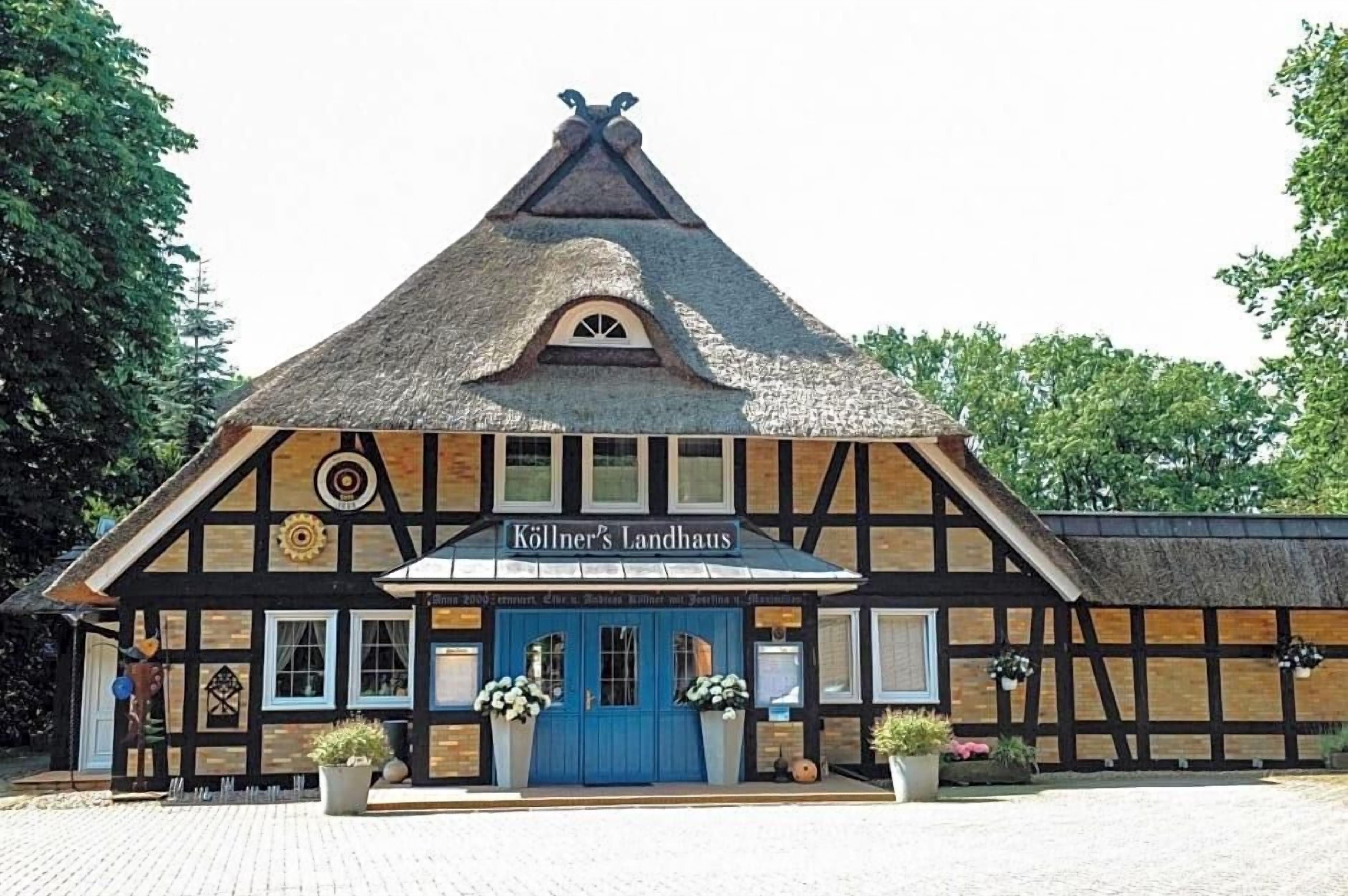 A traditional half-timbered building with a thatched roof, a blue door, and a sign reading 'Köllner's Landhaus.'
