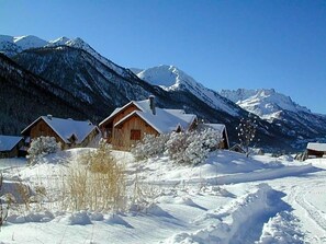 Paisaje montañoso cubierto de nieve con cabañas de madera.
