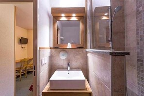 Un baño moderno con un espejo grande, un lavamanos rectangular y una zona de ducha.