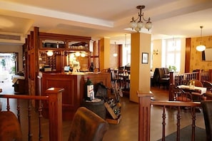 A restaurant with wooden furniture, a bar area, and a staircase leading to another level.