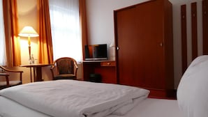 A hotel room with a bed, a desk with a lamp, a television, and a wardrobe. - Hotel Am Dom (Greifswald)