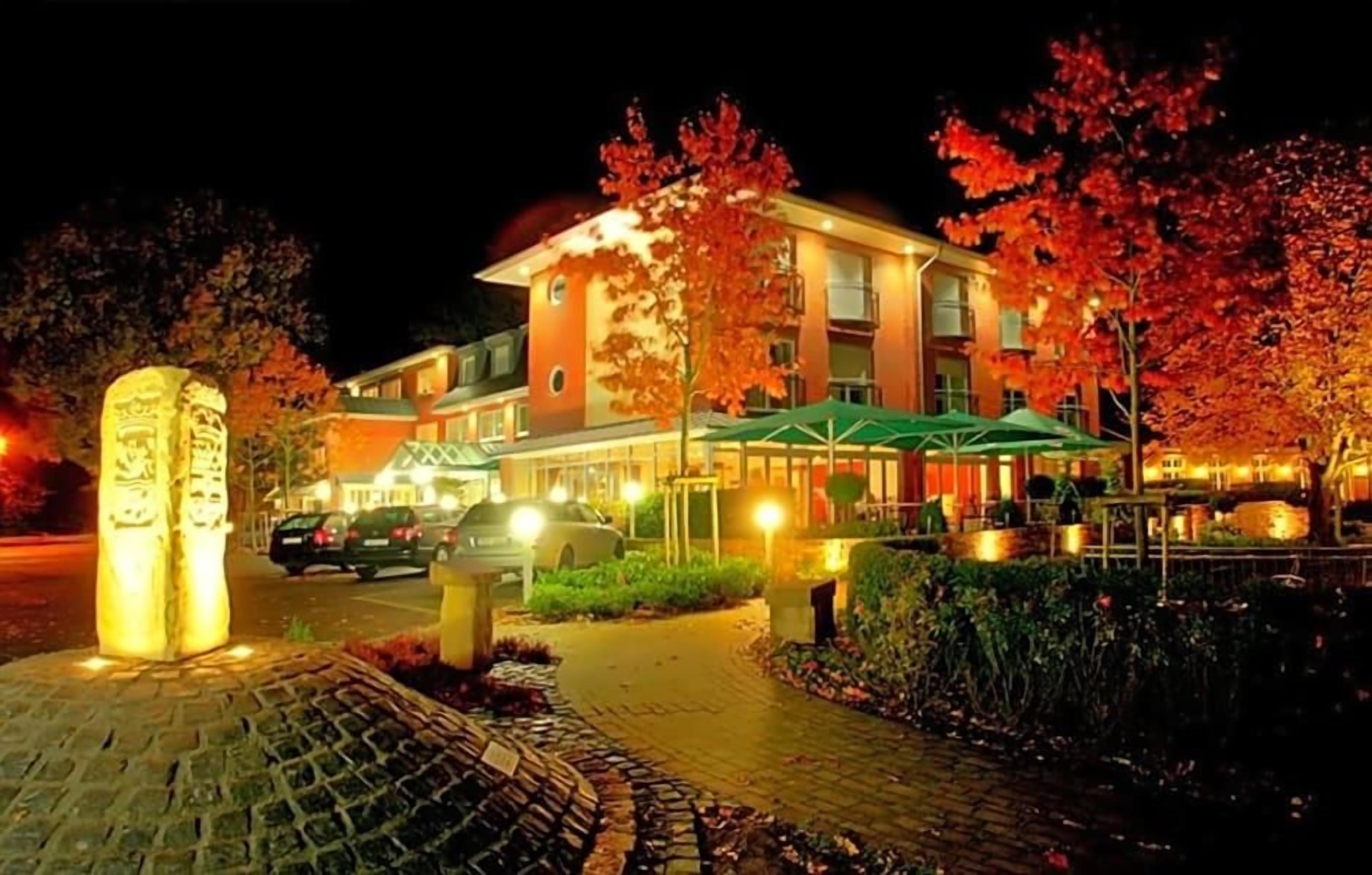 Een hotel met een verharde oprijlaan, een stenen monument en een goed verlichte gevel.