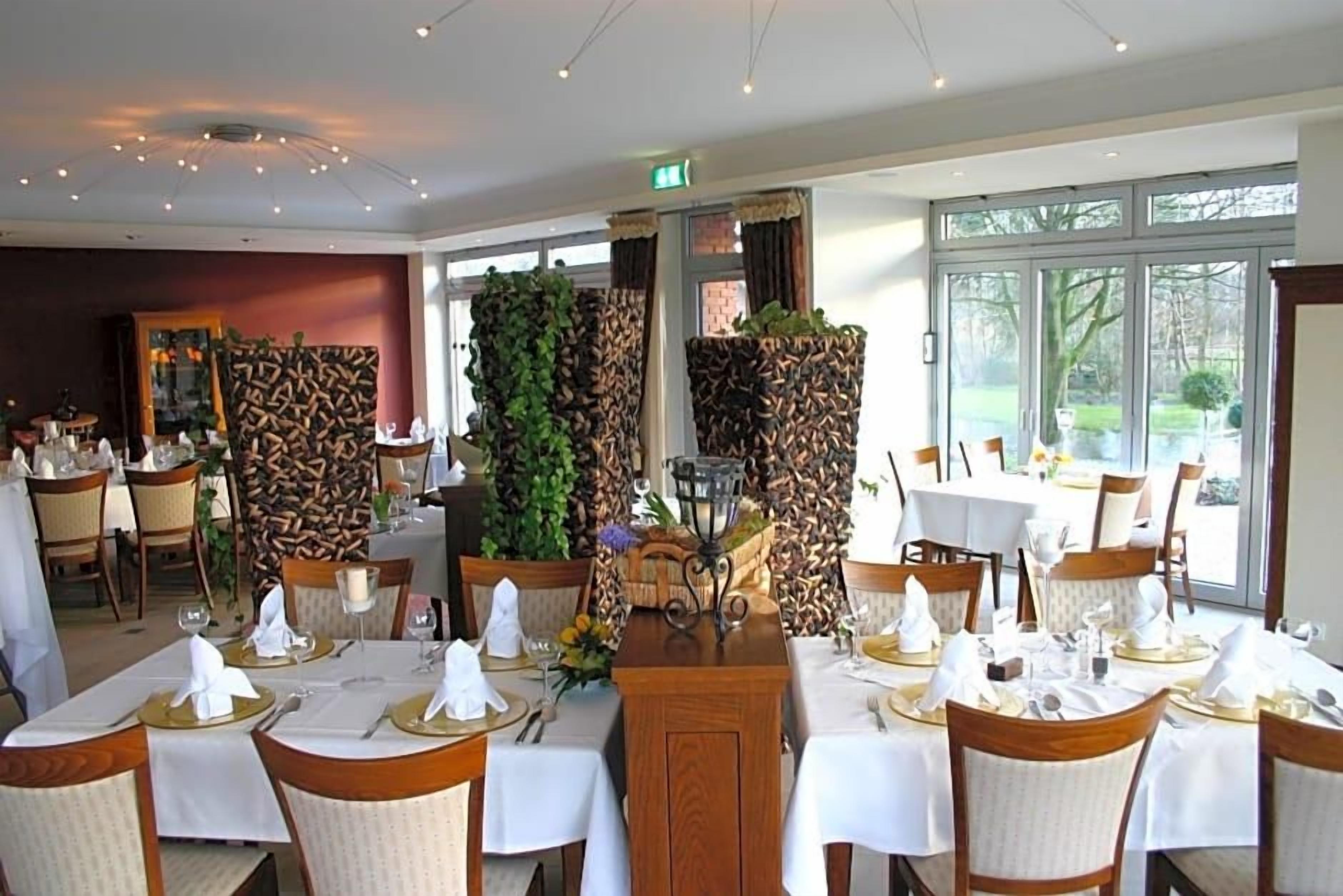 Een restaurant met gedekte tafels, een decoratief middelpunt en uitzicht op het buiten.