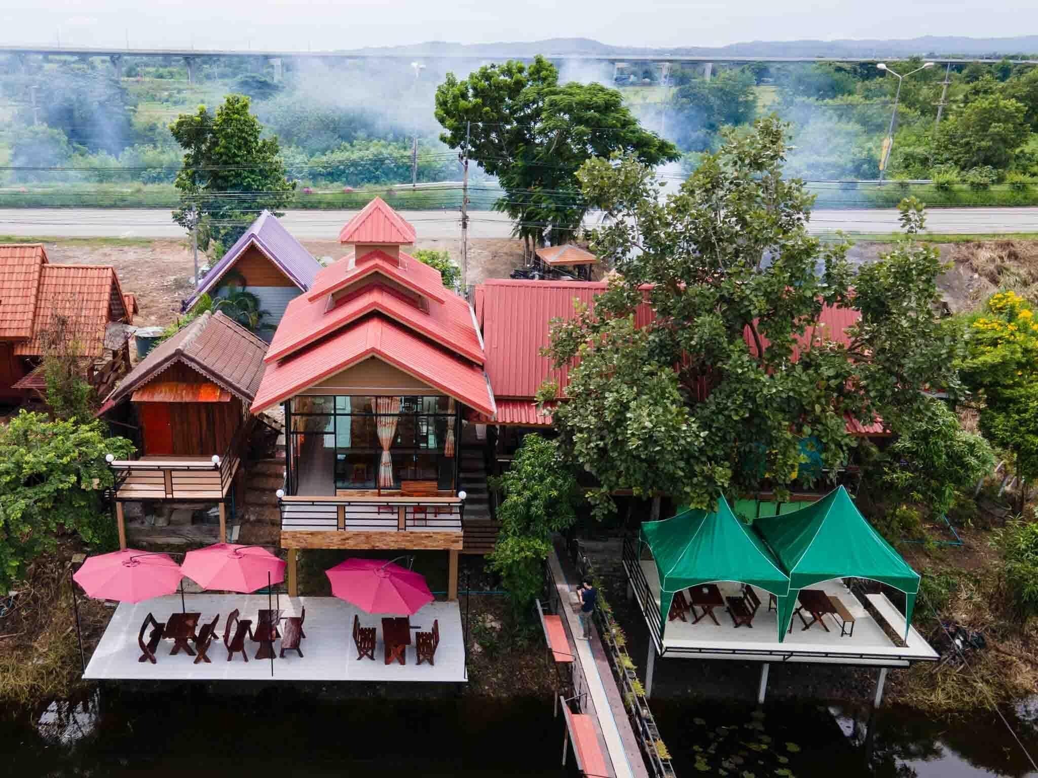 A riverside hotel with multiple buildings, a dock, and a bridge in the background.