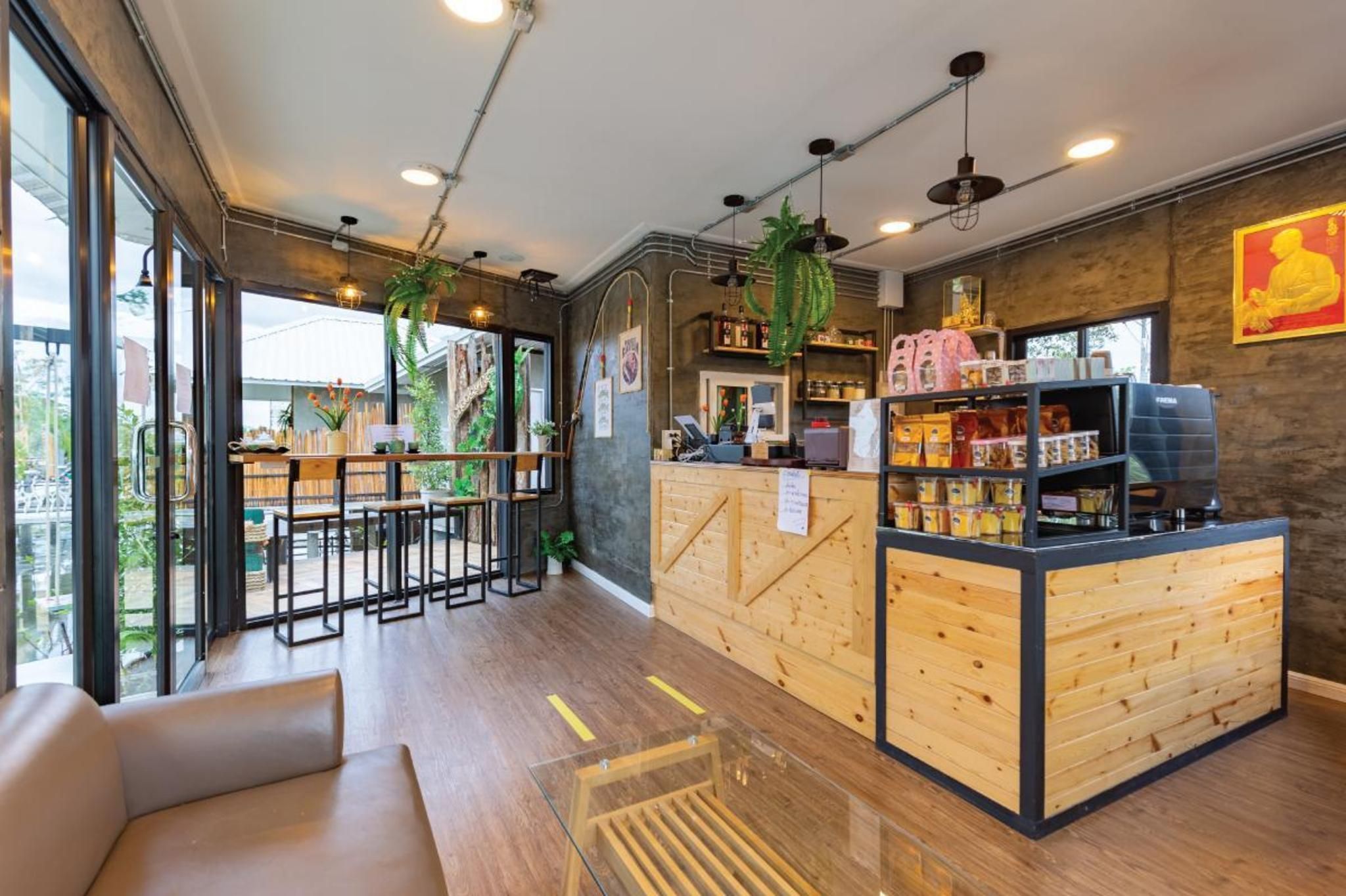 A modern bar area with wooden furniture, a counter with various items, and large windows allowing natural light.