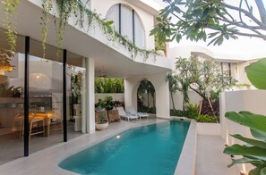 Ein moderner, überdachter Poolbereich mit Pool, Liegestühlen und unterschiedlichen Pflanzen.