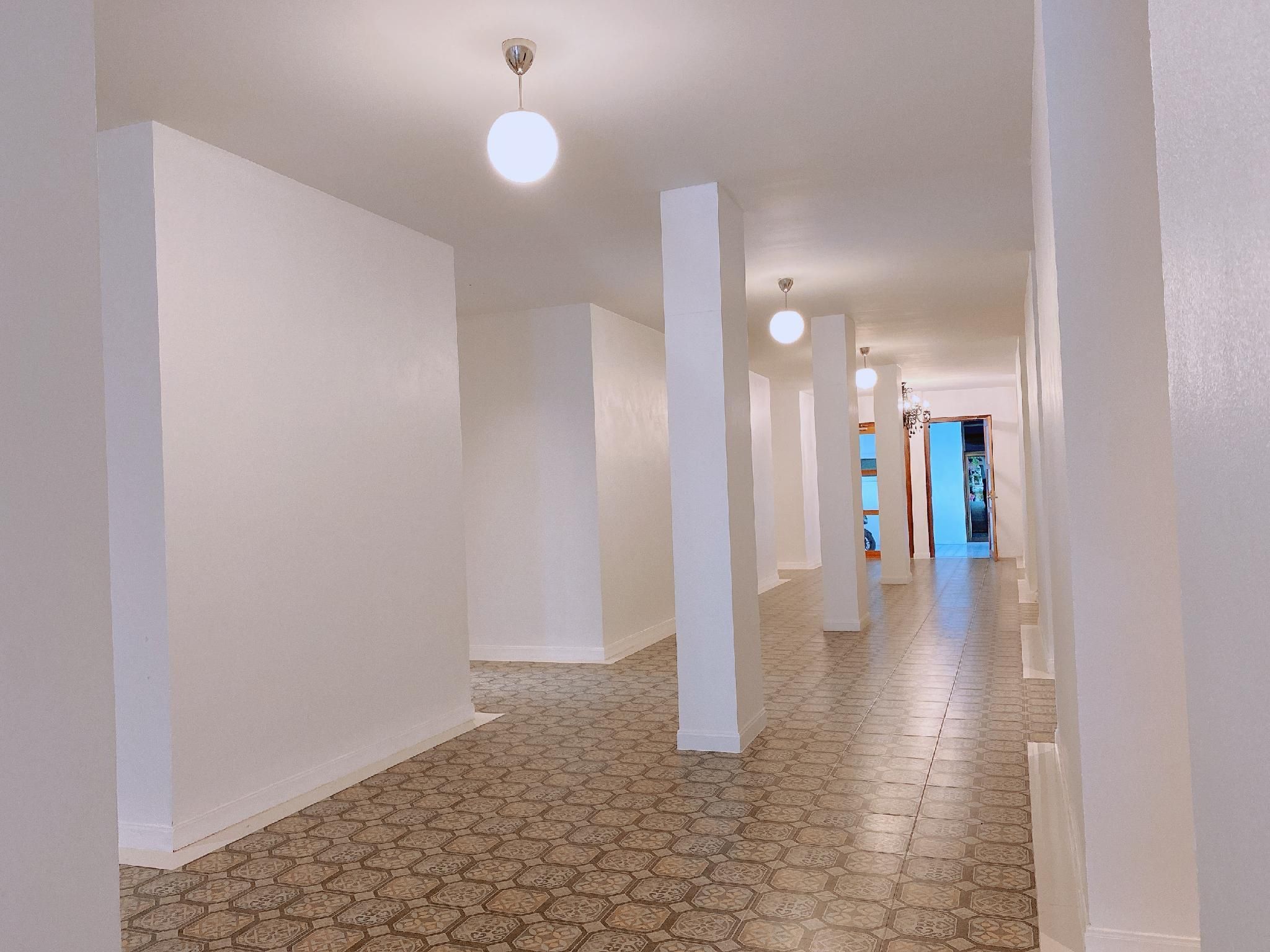 A long, narrow hallway with white walls and a patterned floor.