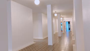A long, narrow hallway with white walls and a patterned floor.