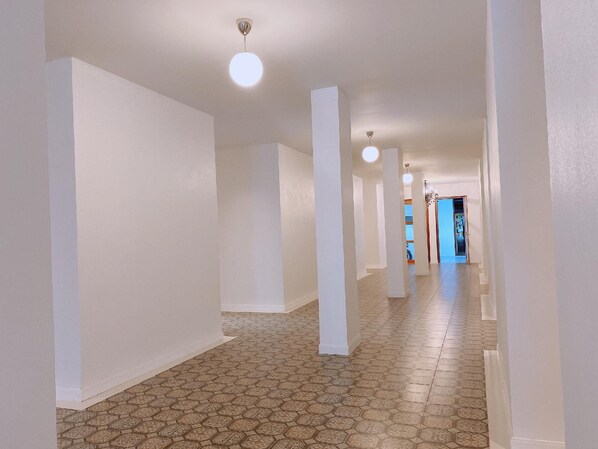 A long, narrow hallway with white walls and a patterned floor.