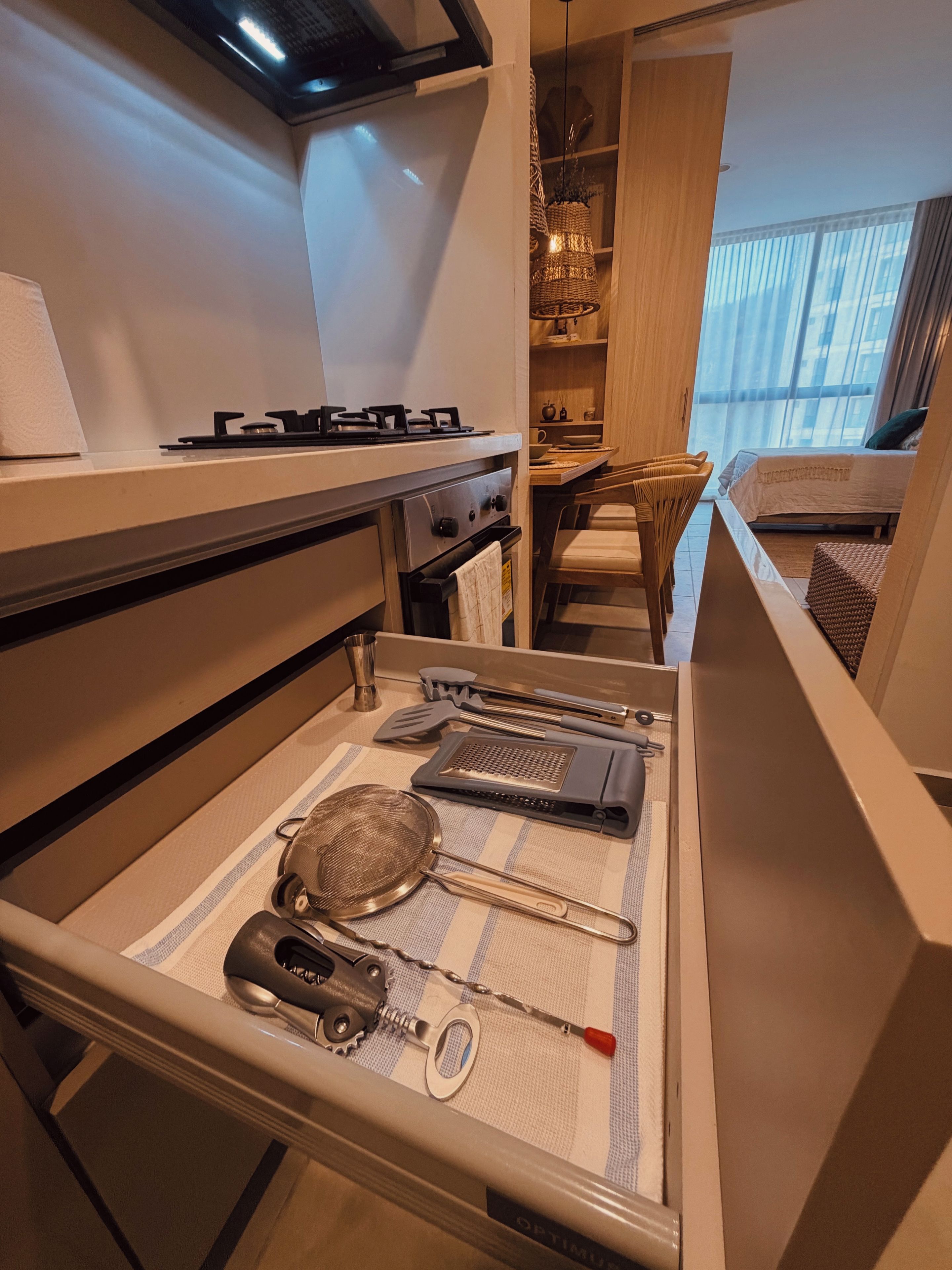 A compact kitchenette with a gas stove, oven, and a drawer containing kitchen utensils.