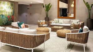 Een moderne lounge met rieten meubels, een grote spiegel en een decoratieve wand.