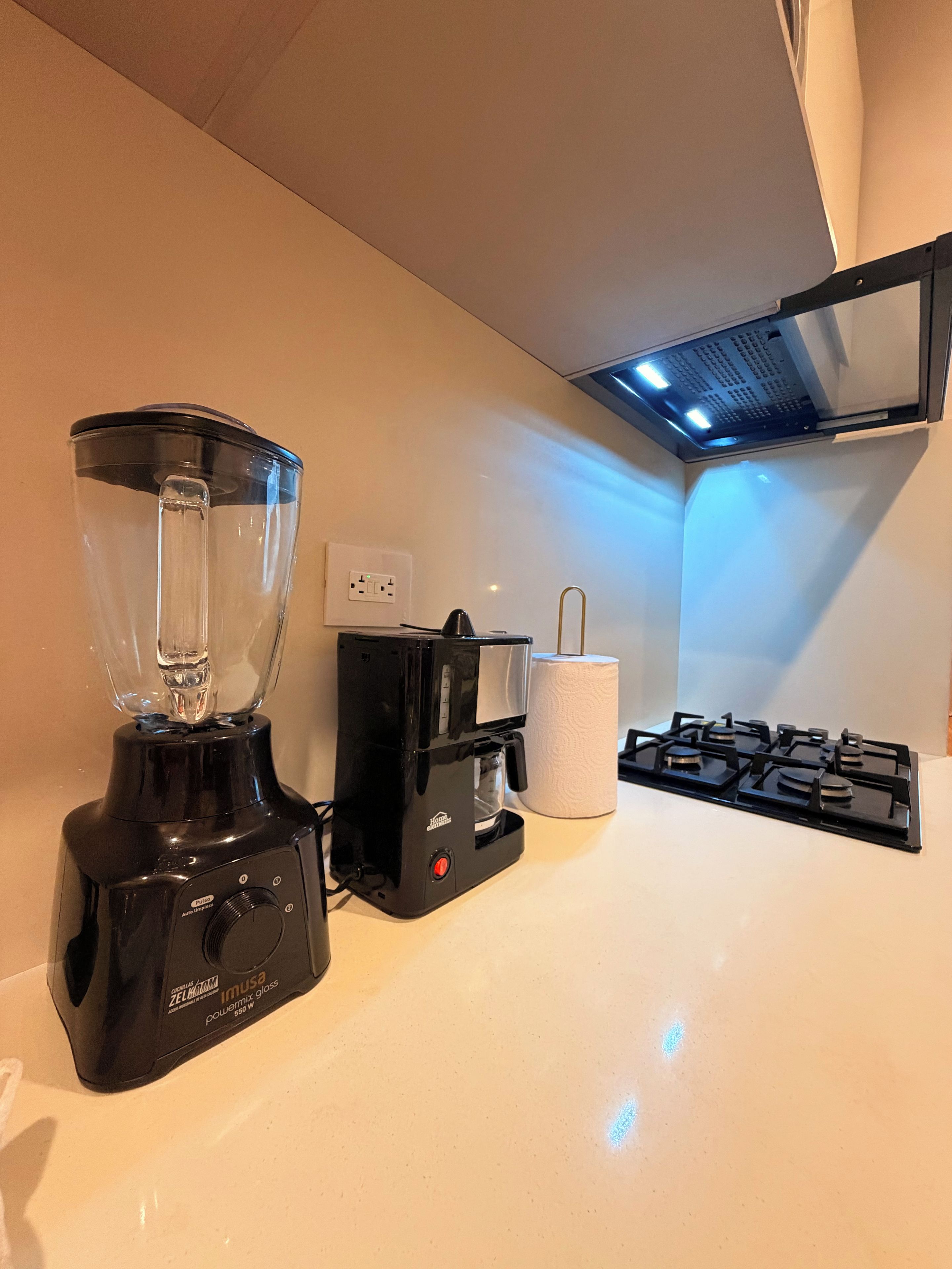 A kitchen with a blender, coffee maker, and gas stove.