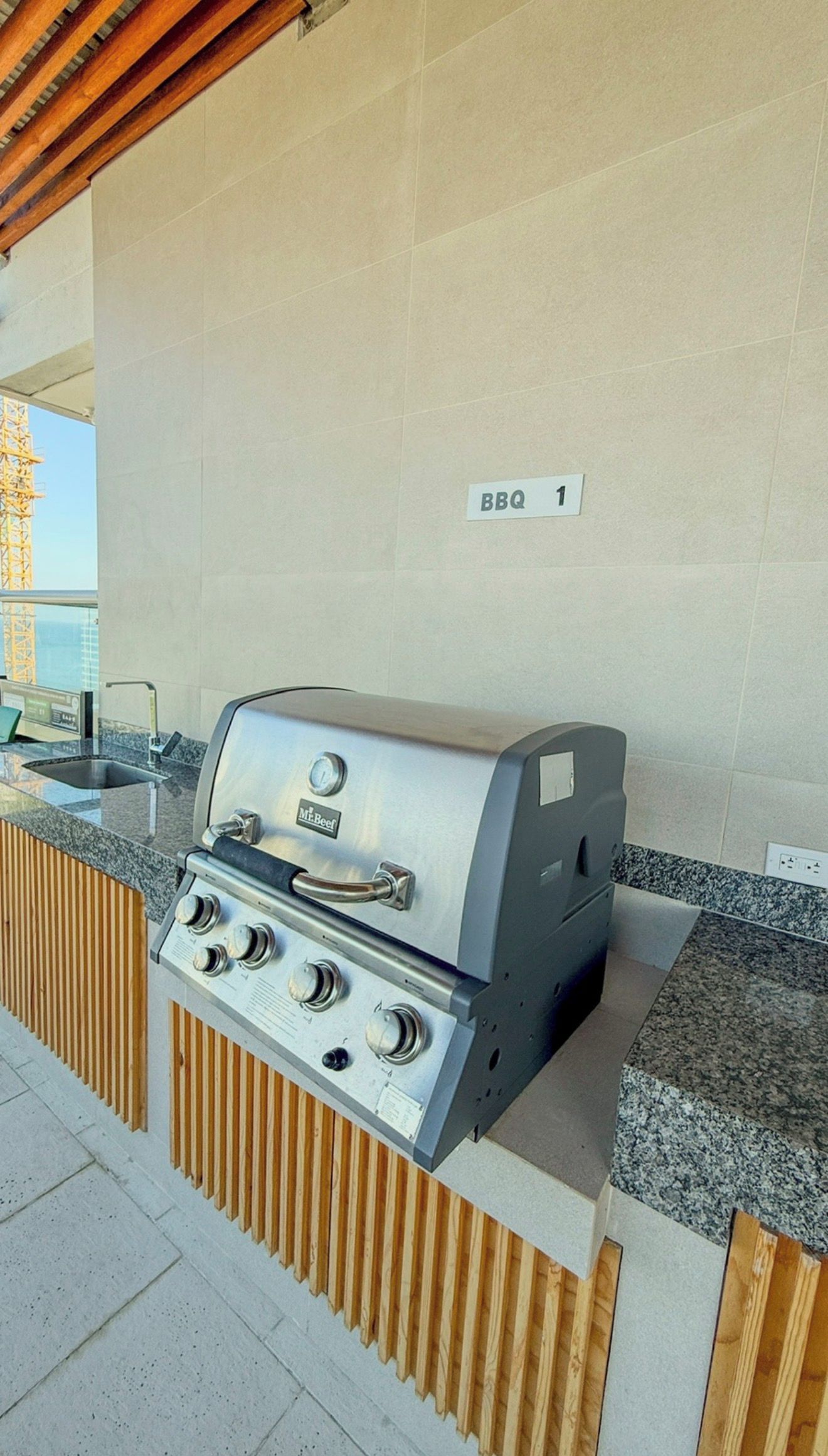 An outdoor grill station with a control panel, a sink, and a wooden panel design.