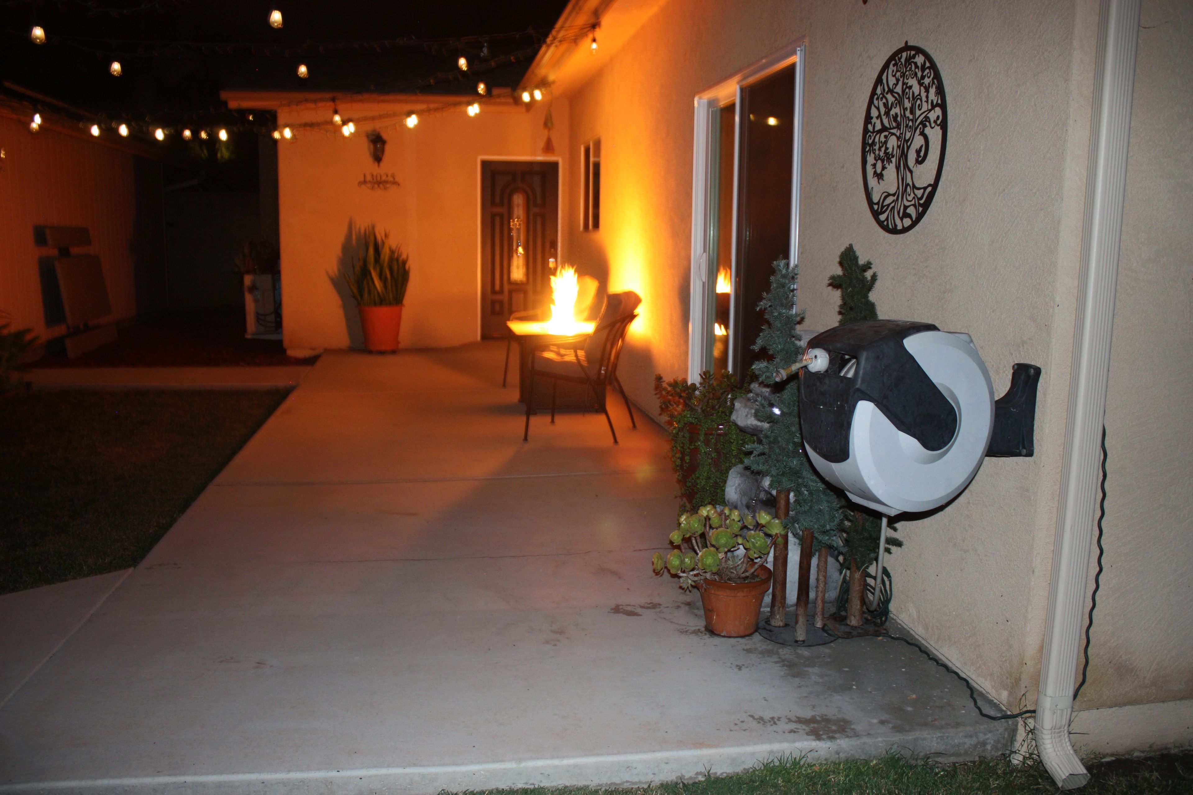 An outdoor patio area with a fire feature, potted plants, and a decorative wall piece.