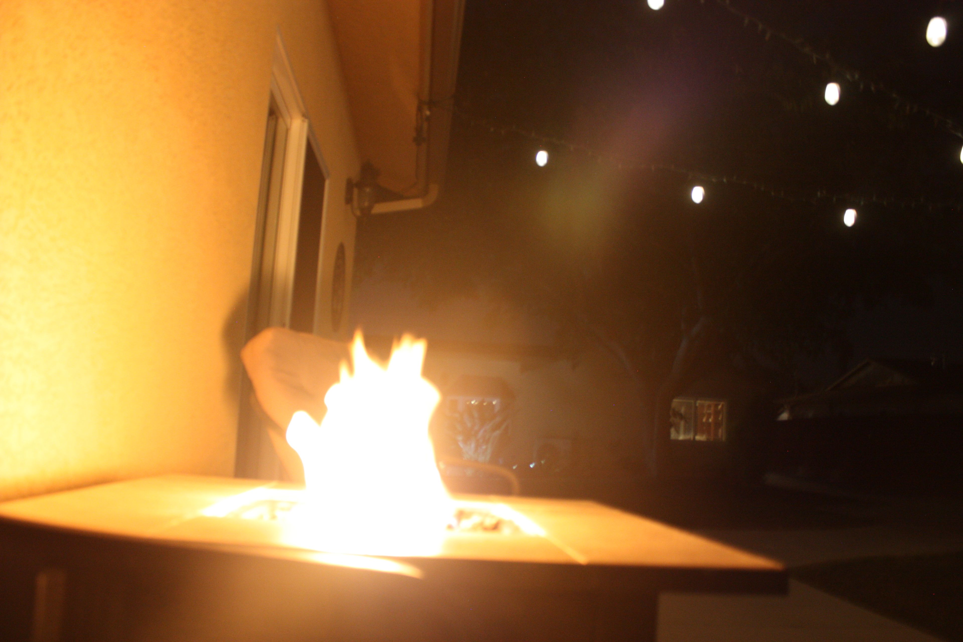 A lit candle in a glass holder on a table.