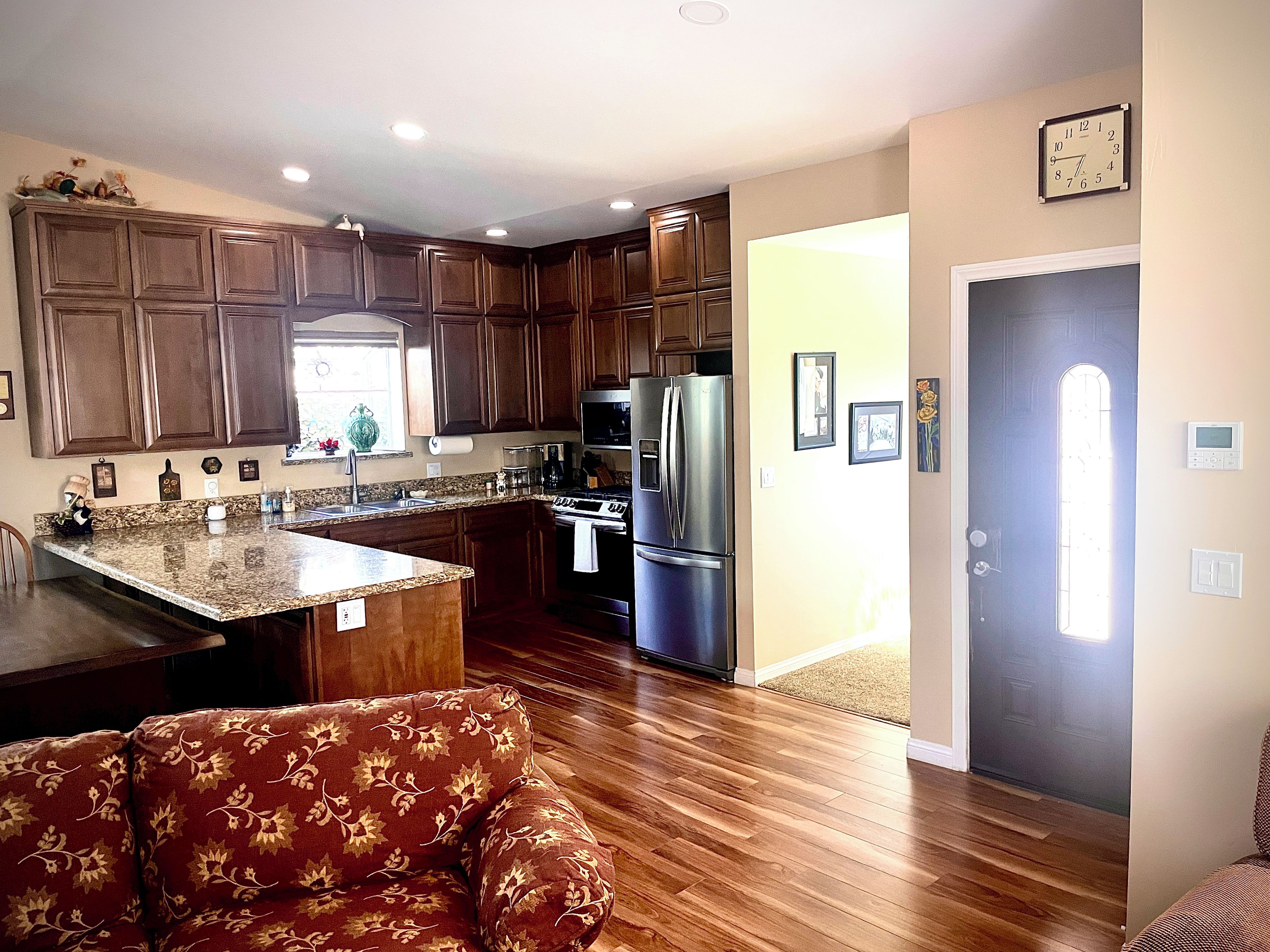 A kitchen with wooden cabinets, a stainless steel refrigerator, and a granite countertop.