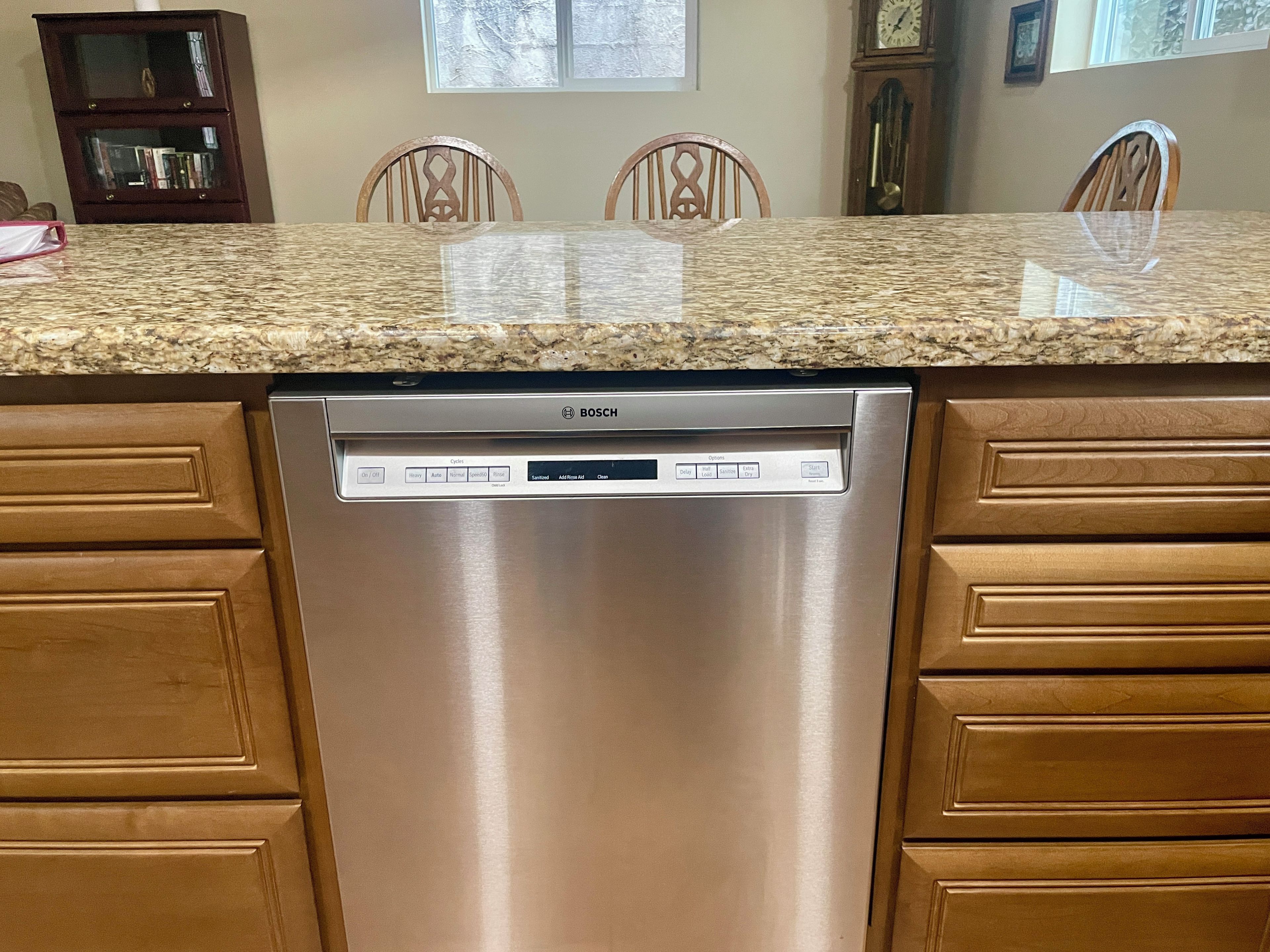 A Bosch dishwasher in a kitchen with wooden cabinets and a granite countertop.