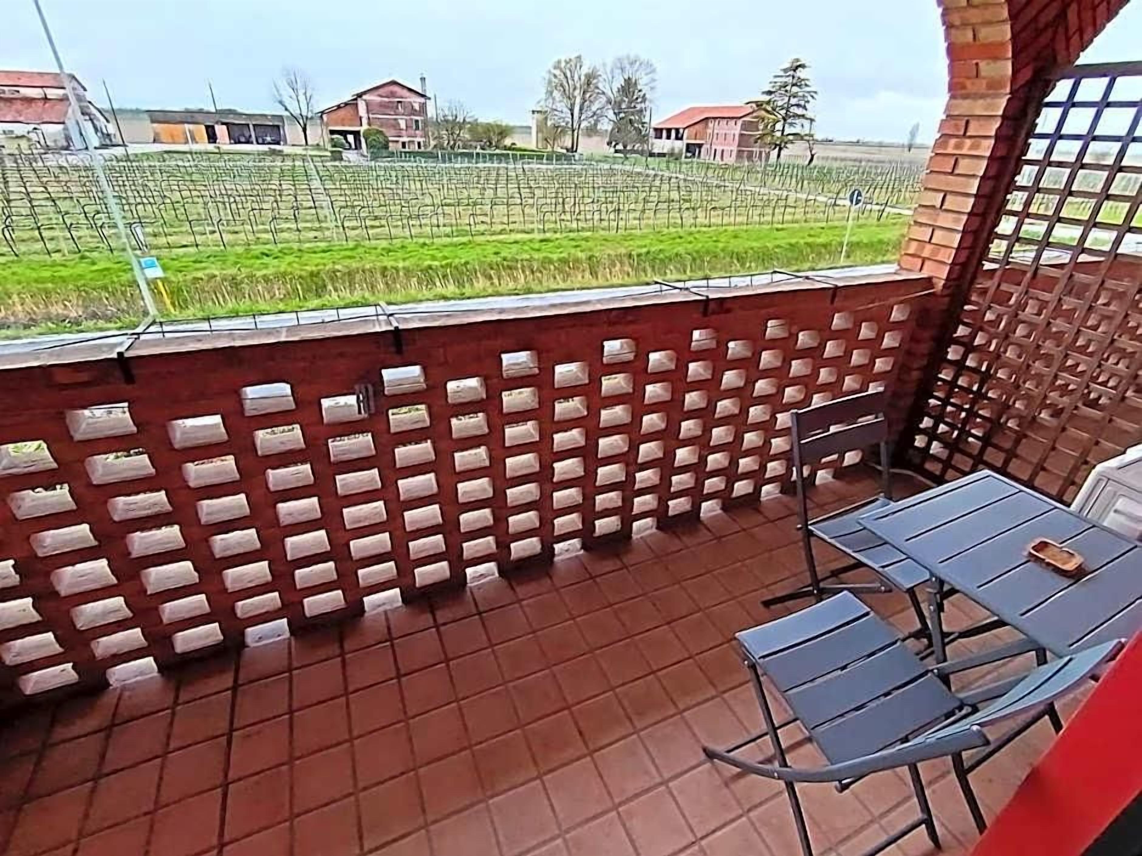 A terrace with a brick wall, a table with chairs, and a view of a vineyard.